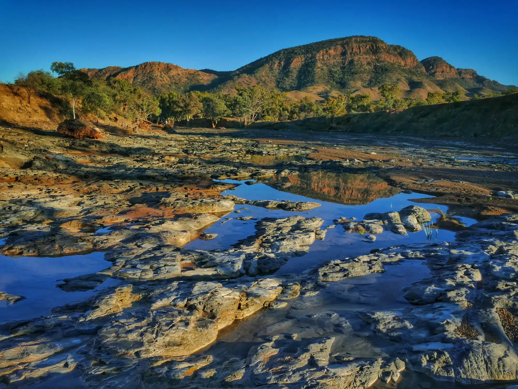 Ikara-Flinders Ranges National Park, South Australia - June 30, 2021:  Early morning light on the Heysen Range is reflected in a pool of water in Brachina Creek.