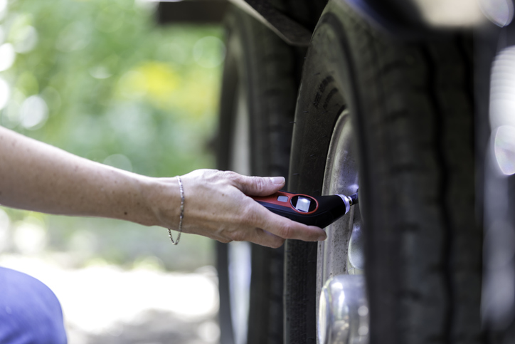 Woman Verifying Tire Pressure on Camper Trailer