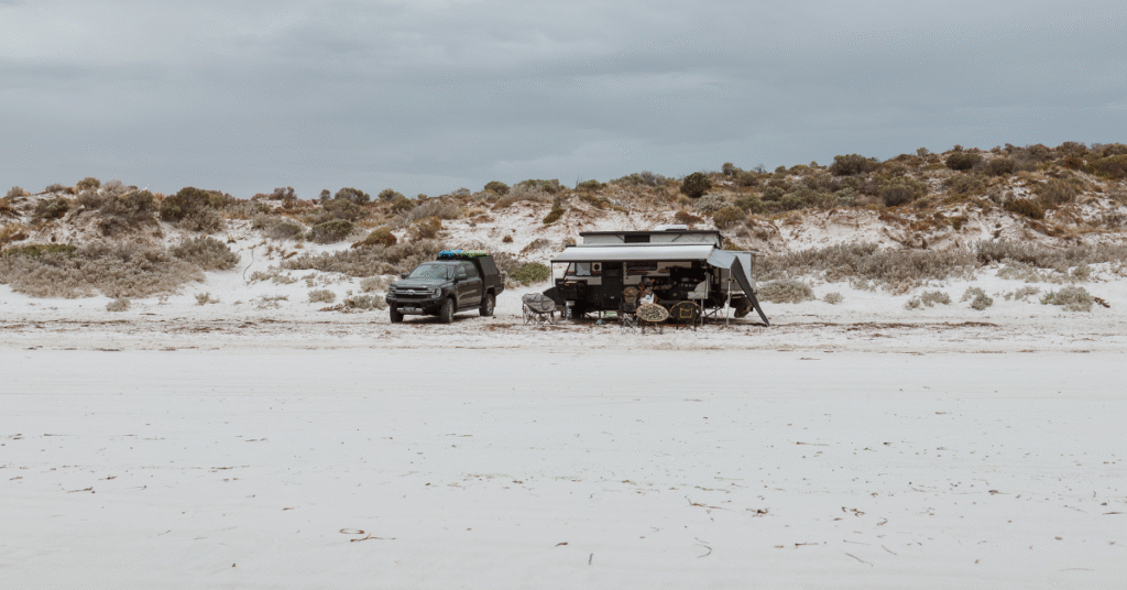 Caravan setup on the beach with blue sky.